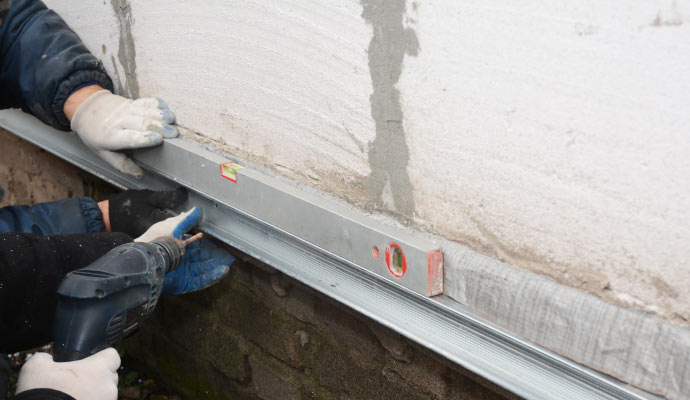 workers repairing basement wall cracks